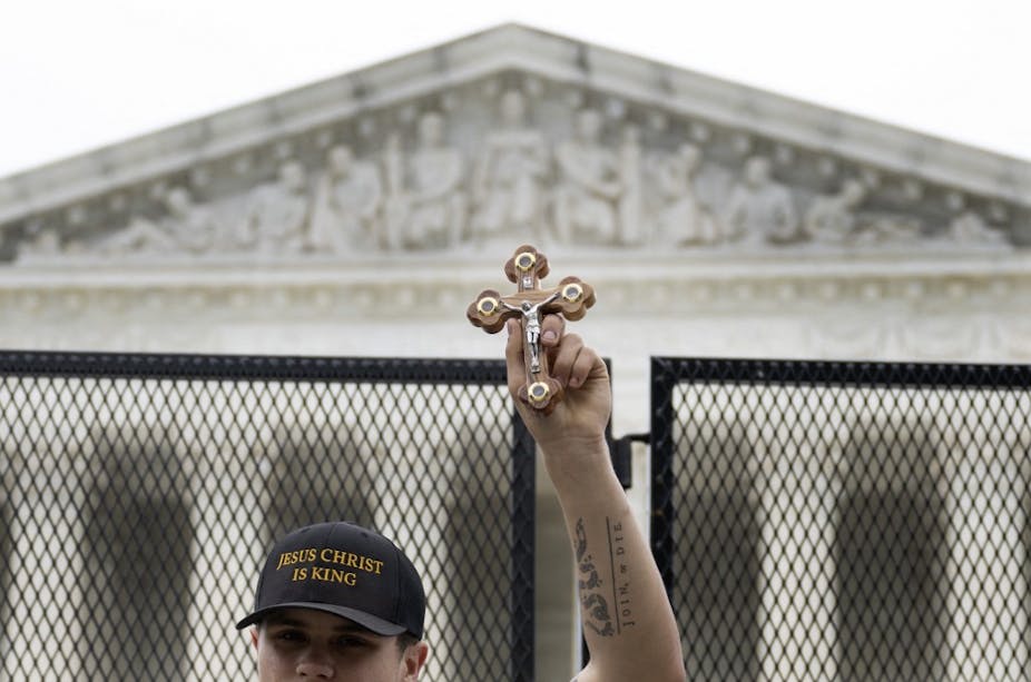 Un homme brandit un crucifix devant le bâtiment de la Cour suprême des États-Unis
