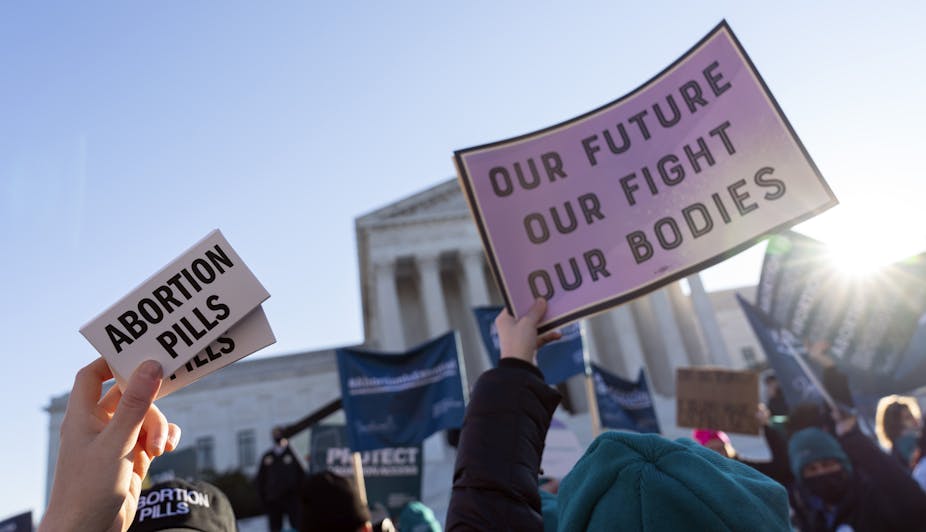 Protestors hold up placards that say 'abortion pills' and 'our future our fight our bodies.'