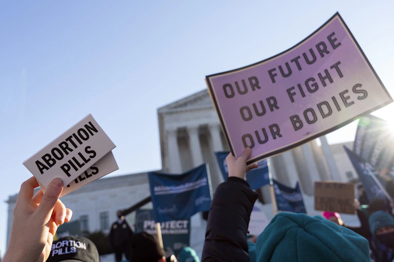Protestors hold up placards that say 'abortion pills' and 'our future our fight our bodies.'