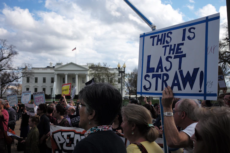 A group of protesters stand outside the White House with placards demanding climate action