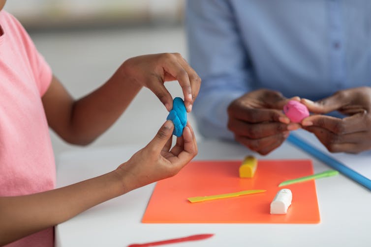 A chlid's hands seen working on play-dough.