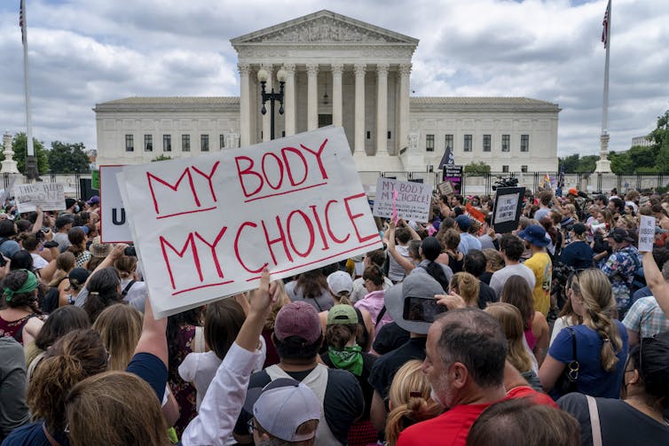 A crowd of protesters seen from behind, outside the U.S. Supreme Court building