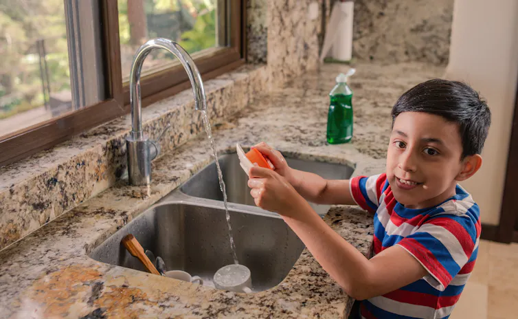 (A child seen washing dishes)