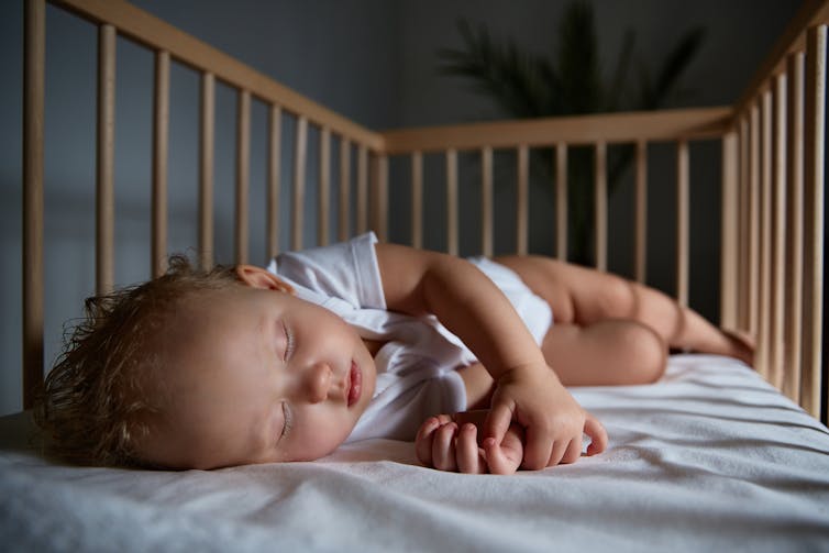 An infant sleeps inside a crib.