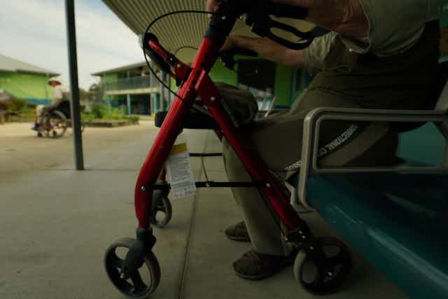 outdoors at a prison facility, two men use mobility aids