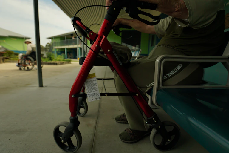 outdoors at a prison facility, two men use mobility aids
