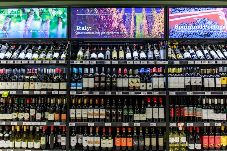 The inside of an alcohol bottle shop. Shelves filled with wine bottles.