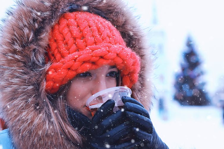 A woman in the snow drinks mulled wine