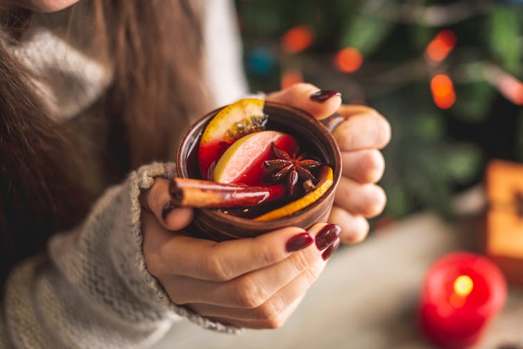 Hands clasp a glass of mulled wine.