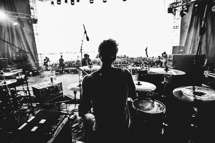 A drummer playing onstage, photographed from the rear