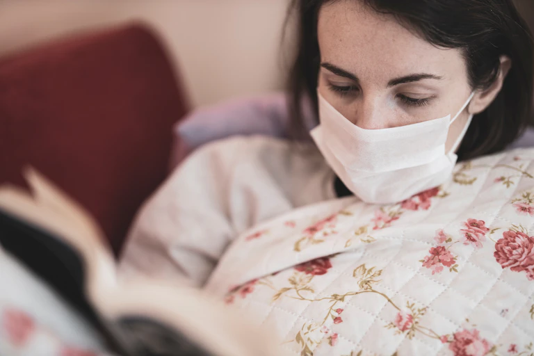Woman in a mask reads a book