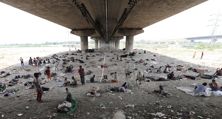 People rest in the shade under a bridge.