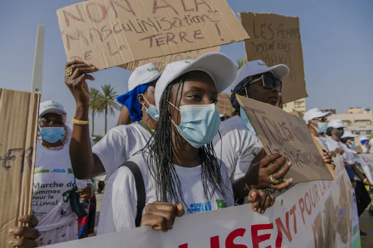 Manifestantes tenant une banderole proclamant « Non à la masculinaisation de la terre »
