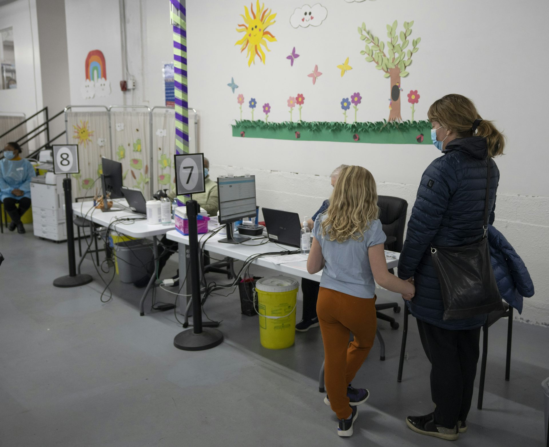 A mother and child stand in a line waiting for a COVID-19 vaccine.