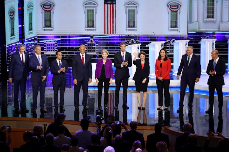 Ten people on a brightly lit stage.