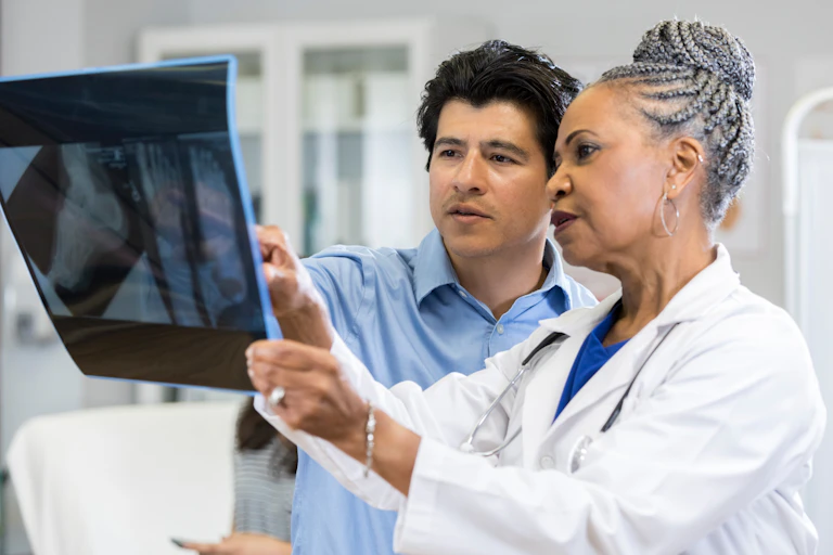 woman in white coat points something out on X-ray to a man
