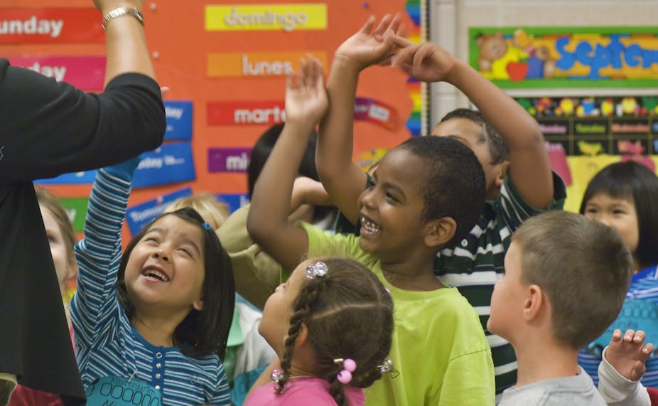 A group of kindergartners high-fiving their teacher