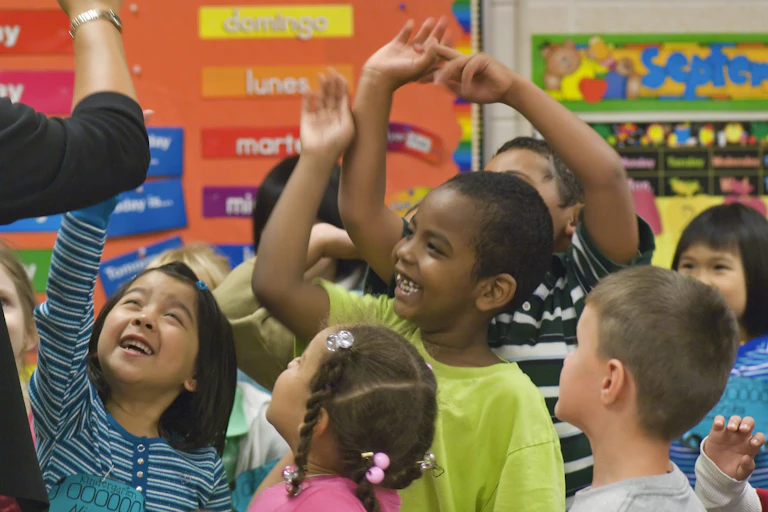 A group of kindergartners high-fiving their teacher