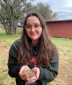 A graduate student with cupped hands filled with small brown larval pods.