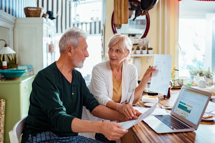 Retired couple discuss finances with computer in front of them.