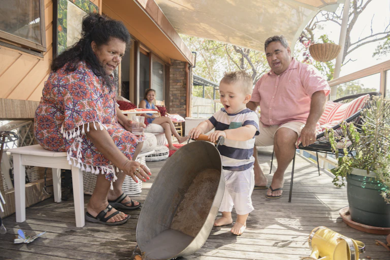 An Aboriginal family are sitting together playing with their infant child.