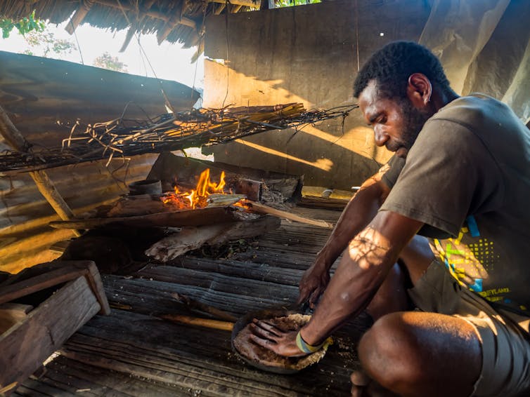 man prepares food over fire