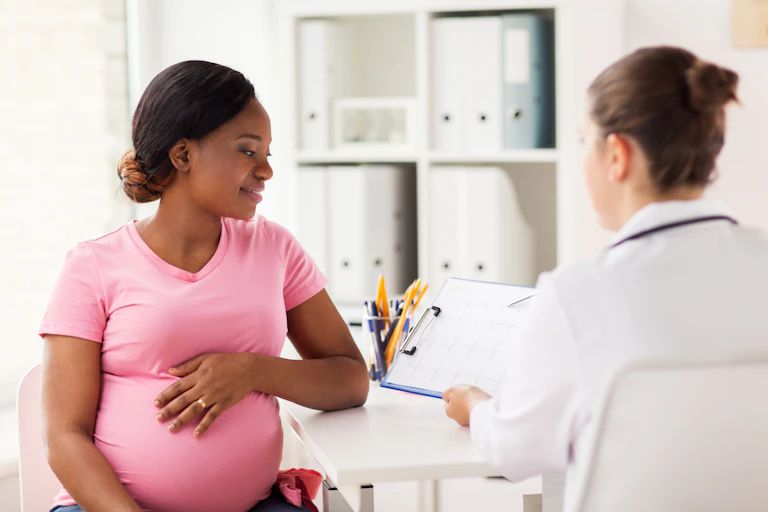 An expectant mother looks at a clipboard her female doctor is showing her.