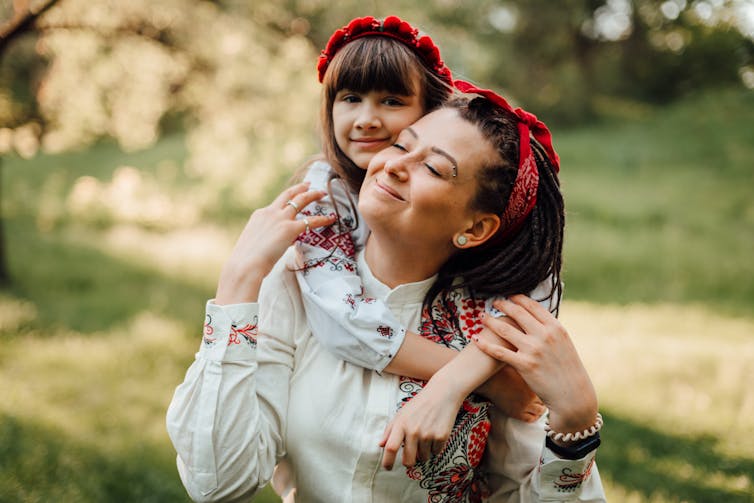 A Ukrainian mother and daughter in traditional embroidered tops with red head scarves.