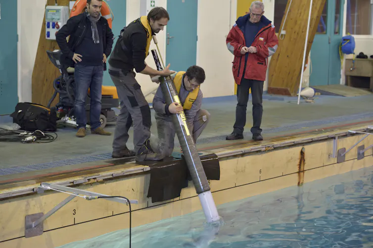 Deux hommes mettent un profileur à l’eau