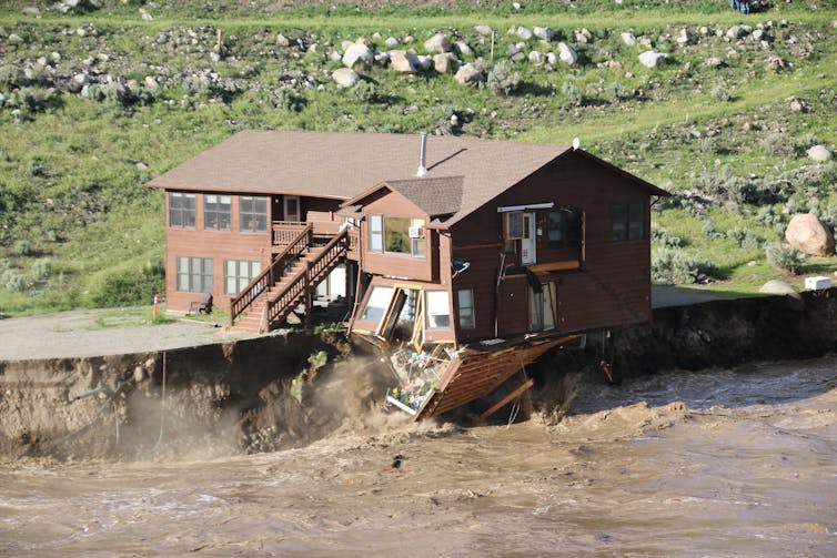 A large two-story building is collapsing after fast-moving water eroded the land under nearly half of it.