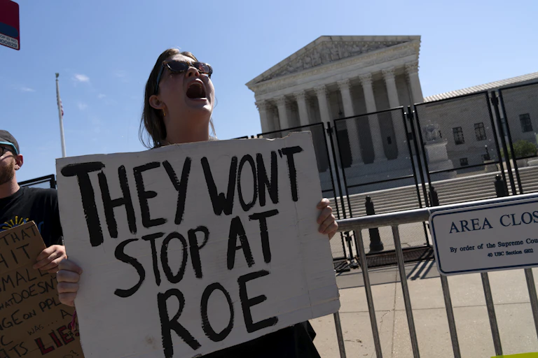 A protester holding a sign saying 'They won't stop at Roe'