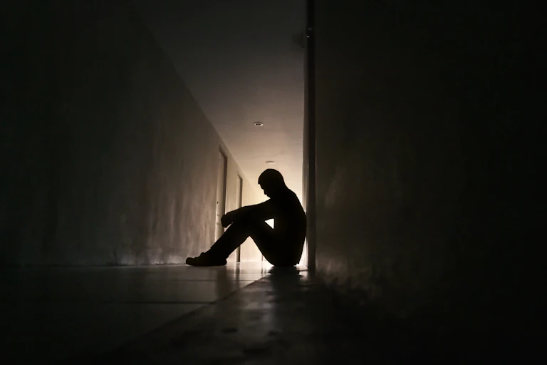 Silhouette depressed man sitting on the ground