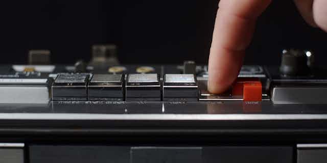 finger pressing button on cassette player.