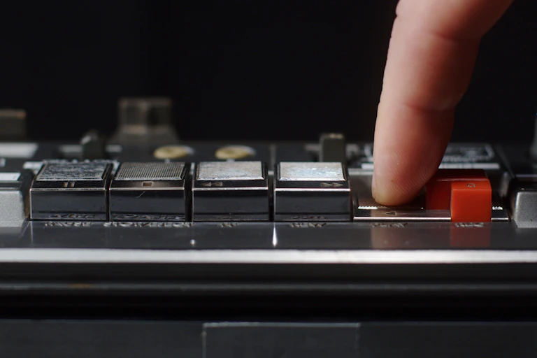 finger pressing button on cassette player.