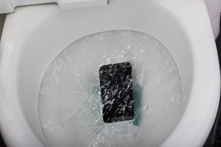 Telefonen tvättas i en toalettskål