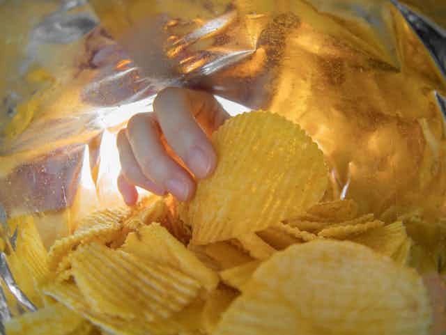 Hand reaching into packet of crisps