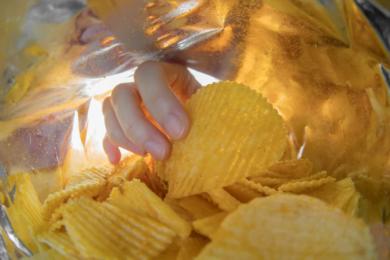 Hand reaching into packet of crisps