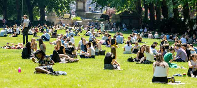People sitting outdoors in a park in London on a sunny day.