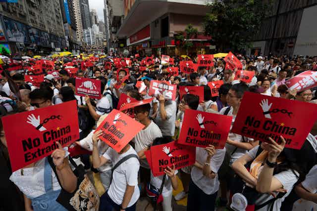 People carrying red placards in a protest.