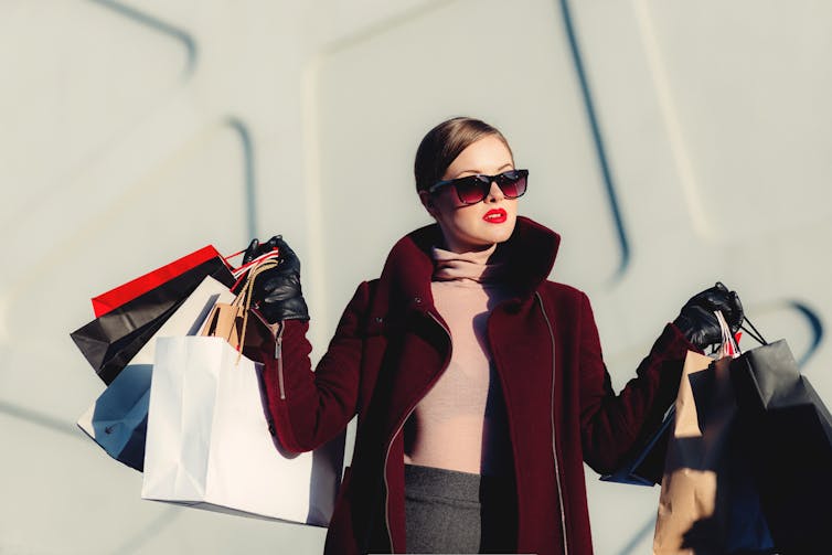 A young woman holds a bunch of shopping bags