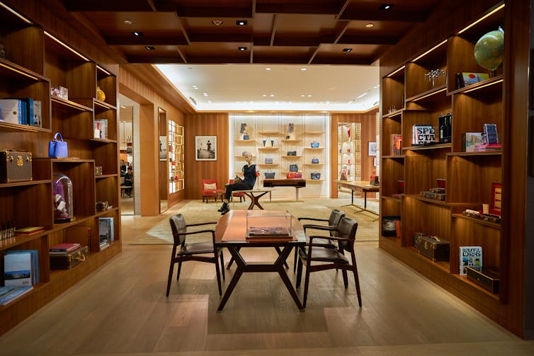 A luxury bag shop is picture with a table in the centre and bags lining either side