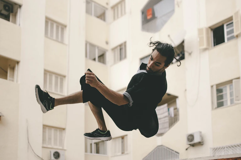 Un homme fait du parkour dans une cité.