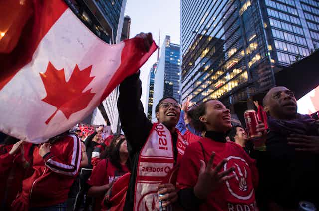 A group of people dance with the Canadian flag.