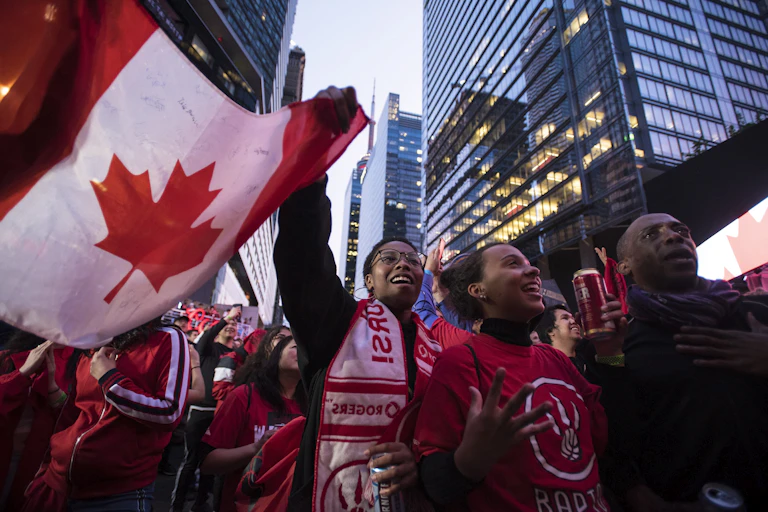 A group of people dance with the Canadian flag.
