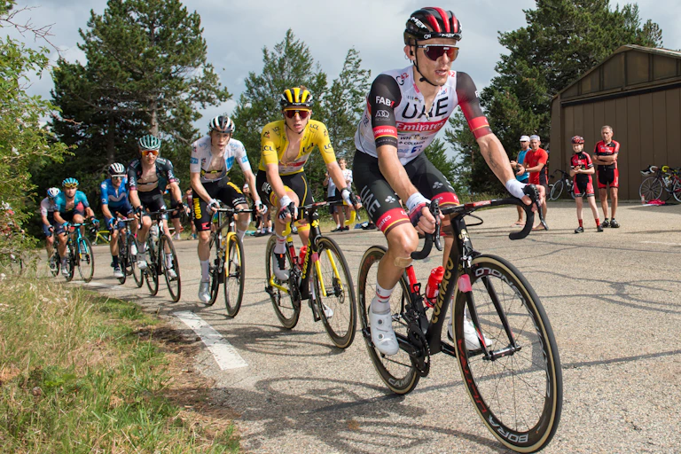 A line of cyclists riding up a hill.