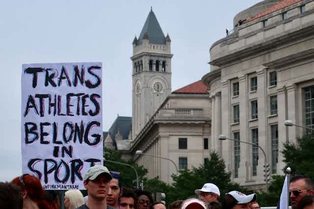 A sign reads 'trans athletes belong in sport'
