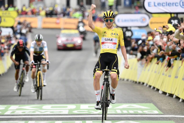 A cyclist with arm in the air crossing the finish line of a race.