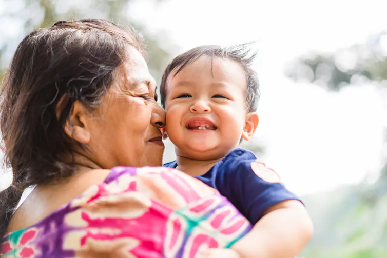 Grandmother cuddling young grandson, nose to cheek