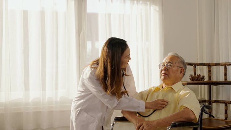 Woman doctor testing heart of man in wheelchair