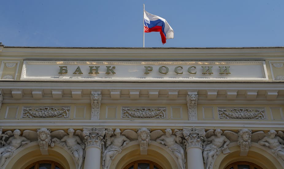 Russian National flag above the sign for 'Bank of Russia' on the Russia's Central Bank headquarters in Moscow, Russia